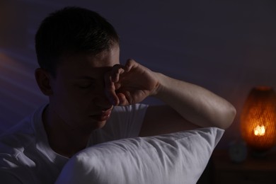 Photo of Frustrated man with pillow suffering from insomnia indoors