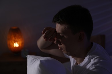 Photo of Frustrated man with pillow suffering from insomnia indoors, space for text