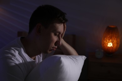 Photo of Frustrated man with pillow suffering from insomnia indoors, space for text