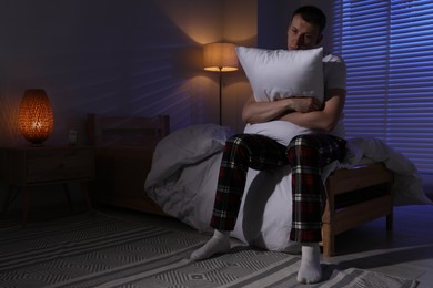 Photo of Frustrated man with pillow suffering from insomnia on bed indoors