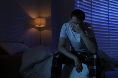 Photo of Frustrated man suffering from insomnia on bed indoors