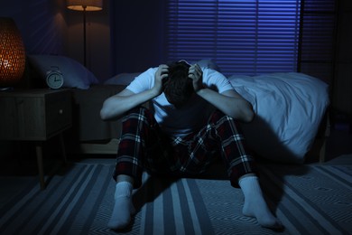 Photo of Frustrated man suffering from insomnia on floor indoors