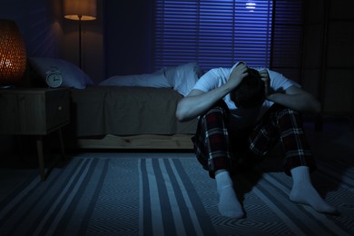 Photo of Frustrated man suffering from insomnia on floor indoors, space for text