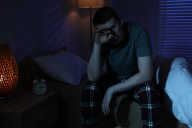 Photo of Frustrated man suffering from insomnia on bed indoors