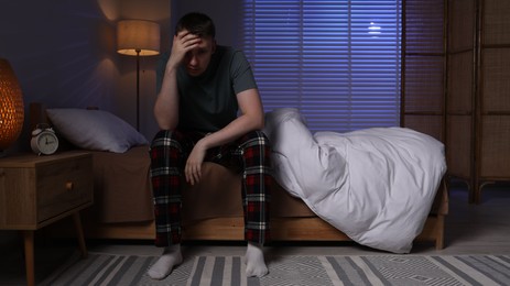 Photo of Frustrated man suffering from insomnia on bed indoors