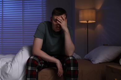 Photo of Frustrated man suffering from insomnia on bed indoors