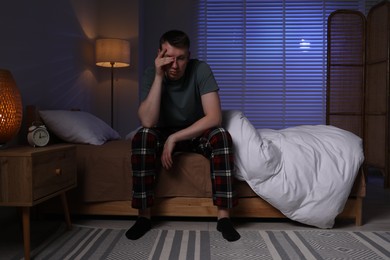 Photo of Frustrated man suffering from insomnia on bed indoors