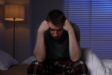 Photo of Frustrated man suffering from insomnia on bed indoors
