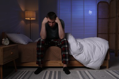 Photo of Frustrated man suffering from insomnia on bed indoors