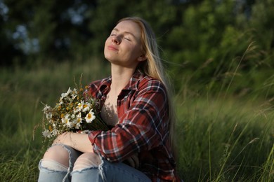 Photo of Beautiful woman with wildflowers enjoying summer day in meadow. Space for text
