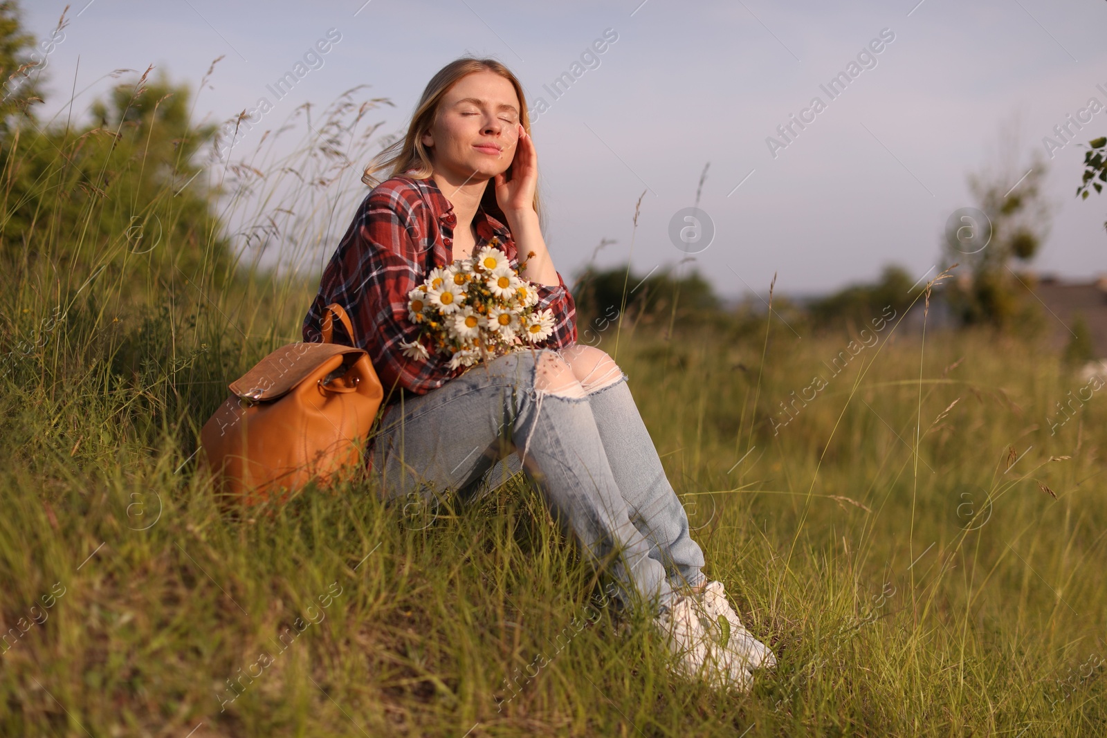 Beautiful woman with wildflowers and backpack enjoying summer day in meadow. Space for text Photo of Beautiful woman with wildflowers and backpack enjoying summer day in meadow. Space for text