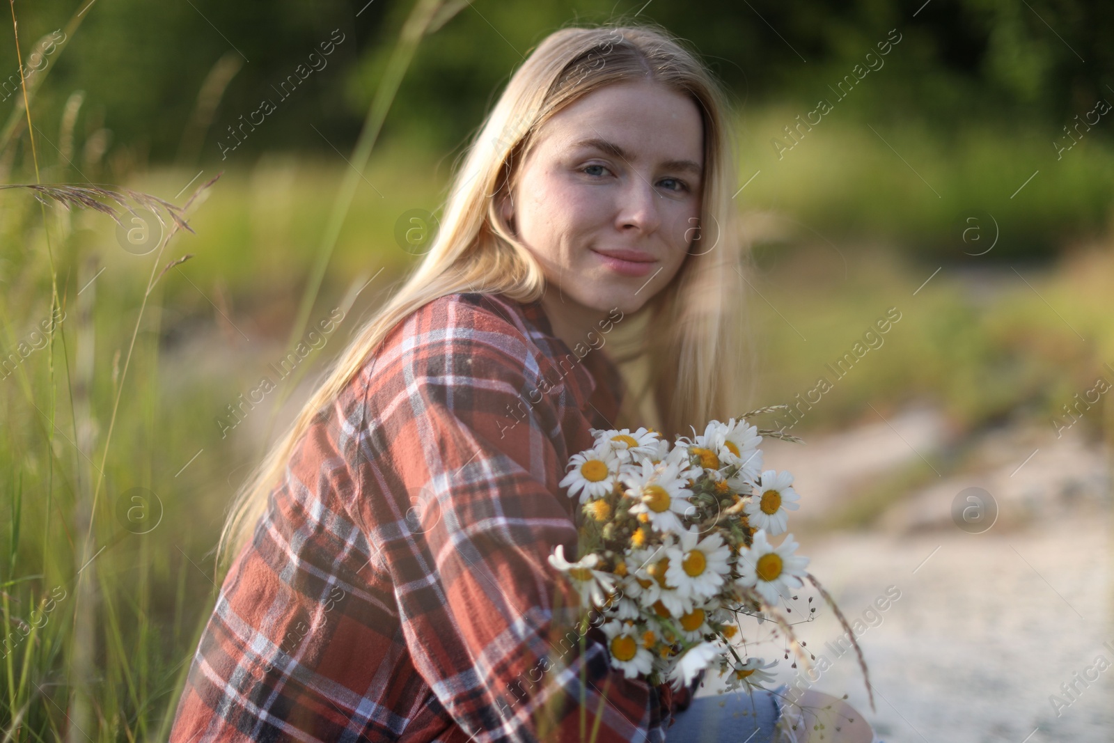 Beautiful woman with bouquet of wildflowers in meadow Photo of Beautiful woman with bouquet of wildflowers in meadow