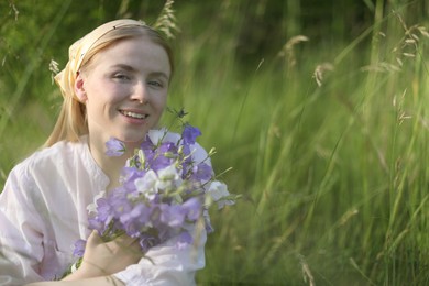 Photo of Beautiful woman with bouquet of wildflowers in meadow. Space for text