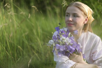 Photo of Beautiful woman with bouquet of wildflowers in meadow. Space for text