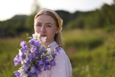 Photo of Beautiful woman with bouquet of wildflowers in meadow on sunny day. Space for text