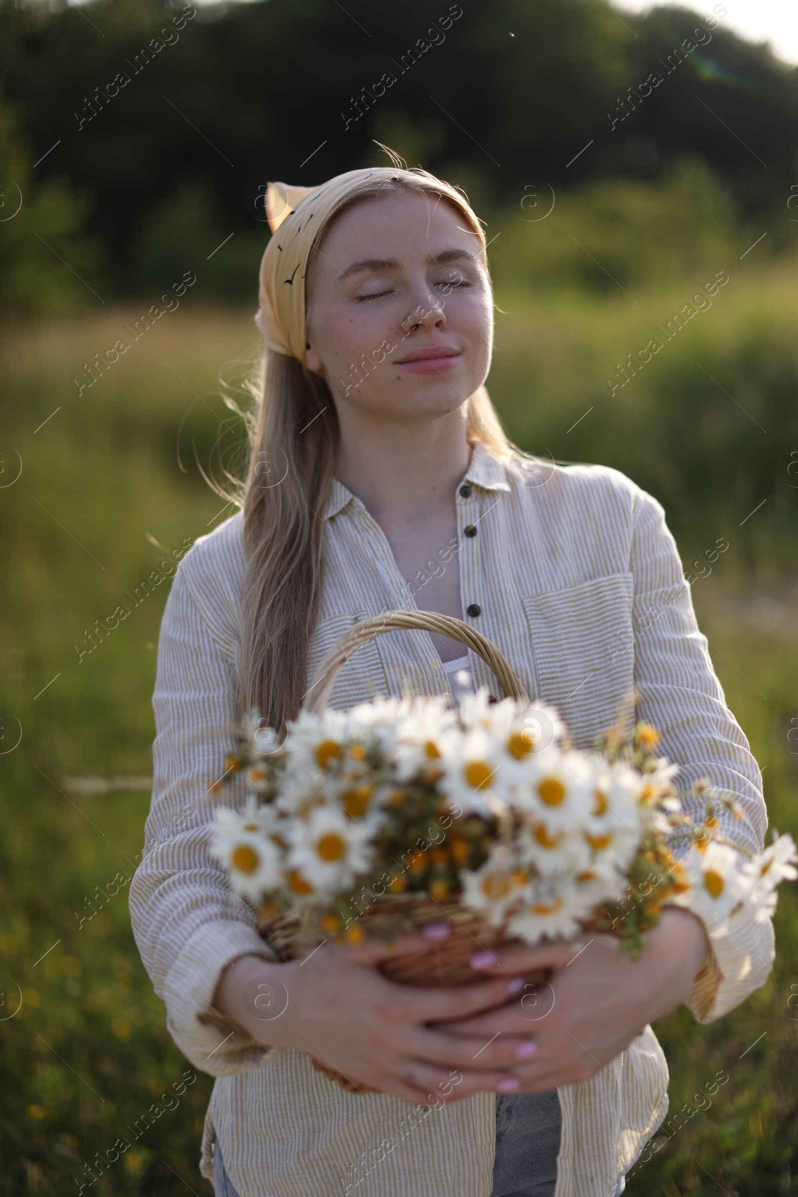Happy woman with basket full of beautiful wildflowers outdoors Photo of Happy woman with basket full of beautiful wildflowers outdoors