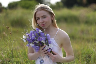Photo of Beautiful woman with bouquet of wildflowers enjoying sunny day in meadow