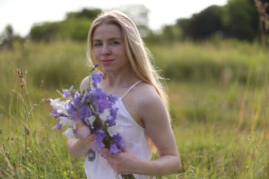 Photo of Beautiful woman with bouquet of wildflowers enjoying sunny day in meadow