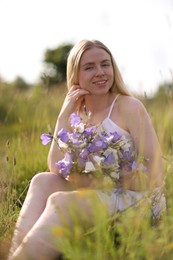 Photo of Beautiful woman with bouquet of wildflowers enjoying sunny day in meadow