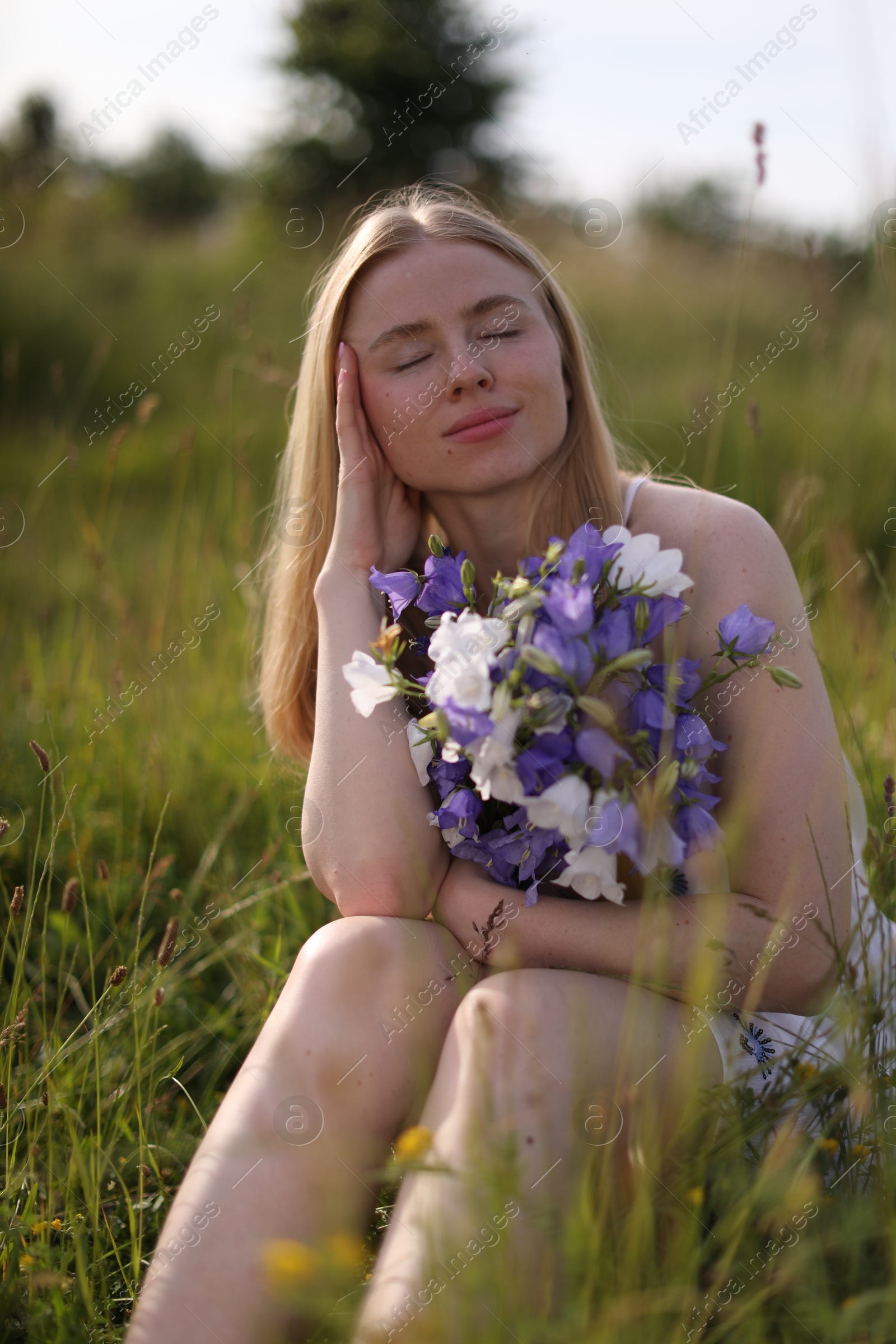 Photo of Beautiful woman with bouquet of wildflowers enjoying sunny day in meadow
