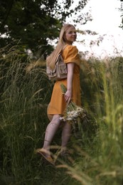 Photo of Beautiful woman with bouquet of wildflowers in meadow