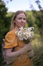 Photo of Beautiful woman with bouquet of wildflowers in meadow