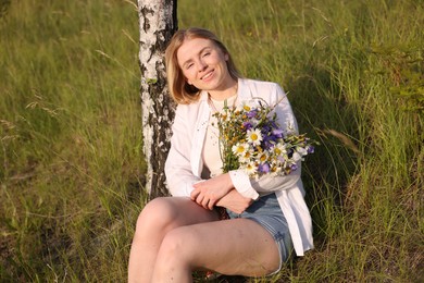 Photo of Woman with bouquet of beautiful wildflowers outdoors on sunny day