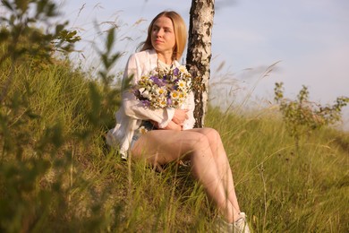 Photo of Woman with bouquet of beautiful wildflowers outdoors on sunny day