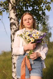Photo of Woman with bouquet of beautiful wildflowers outdoors on sunny day