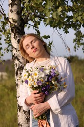 Photo of Woman with bouquet of beautiful wildflowers outdoors on sunny day