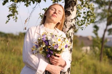 Photo of Woman with bouquet of beautiful wildflowers outdoors on sunny day