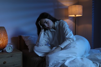 Photo of Frustrated woman suffering from insomnia on bed at home