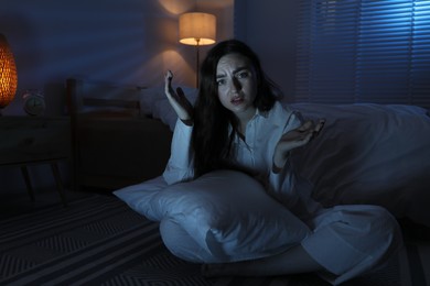 Photo of Frustrated woman with pillow suffering from insomnia on floor at home, space for text