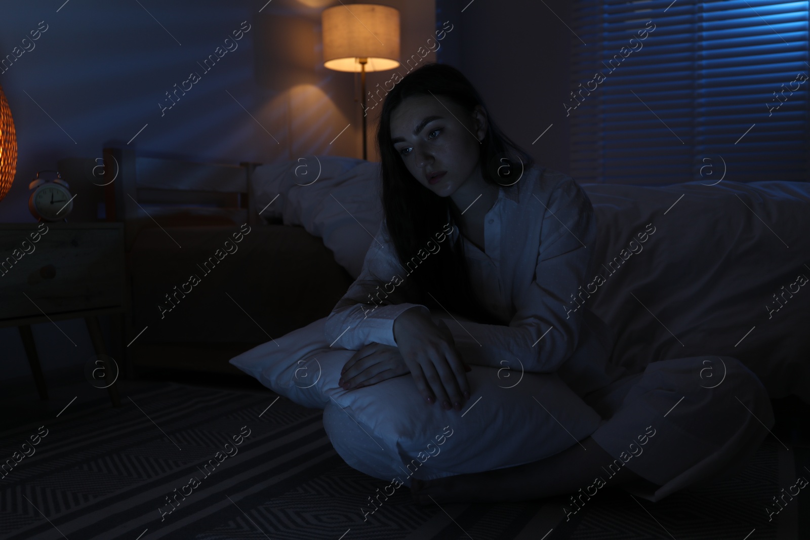 Photo of Frustrated woman with pillow suffering from insomnia on floor at home, space for text