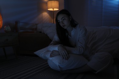 Photo of Frustrated woman with pillow suffering from insomnia on floor at home, space for text