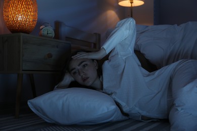 Photo of Frustrated woman with pillow suffering from insomnia on floor at home