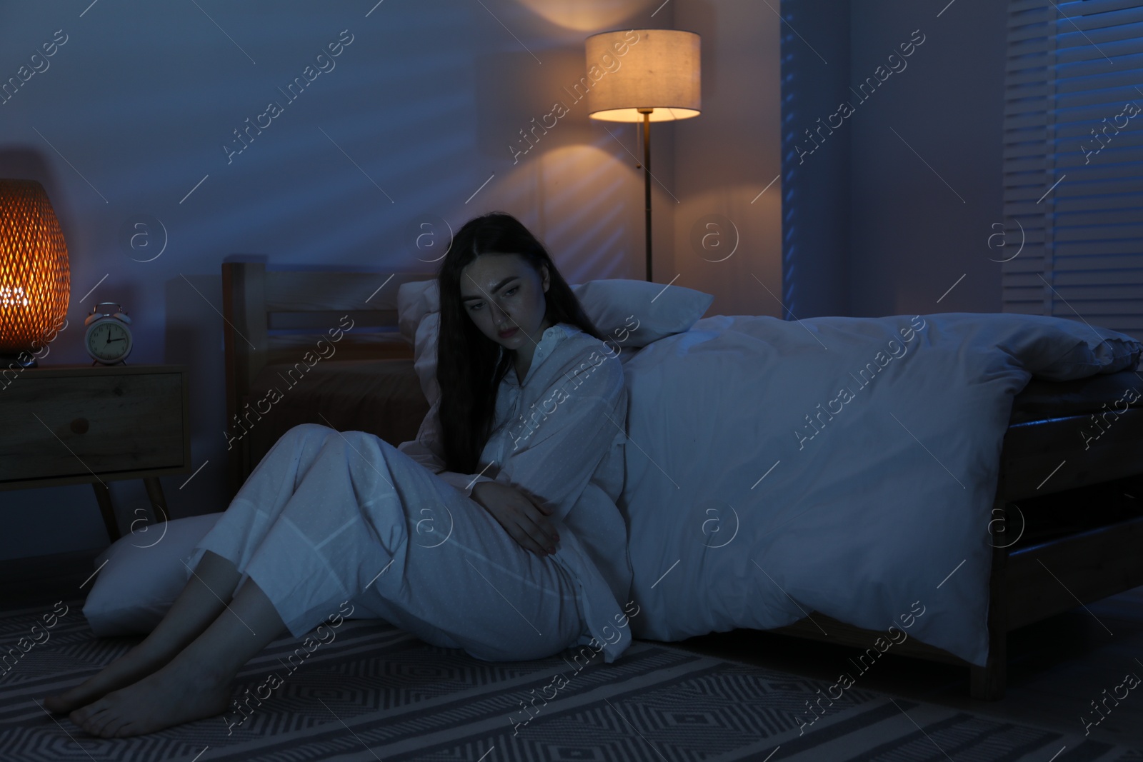 Frustrated woman suffering from insomnia on floor at home Photo of Frustrated woman suffering from insomnia on floor at home