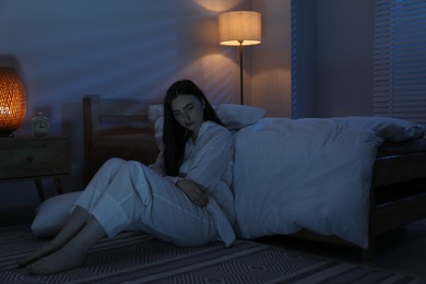 Photo of Frustrated woman suffering from insomnia on floor at home