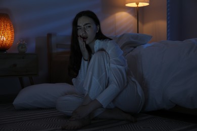 Photo of Frustrated woman suffering from insomnia on floor at home
