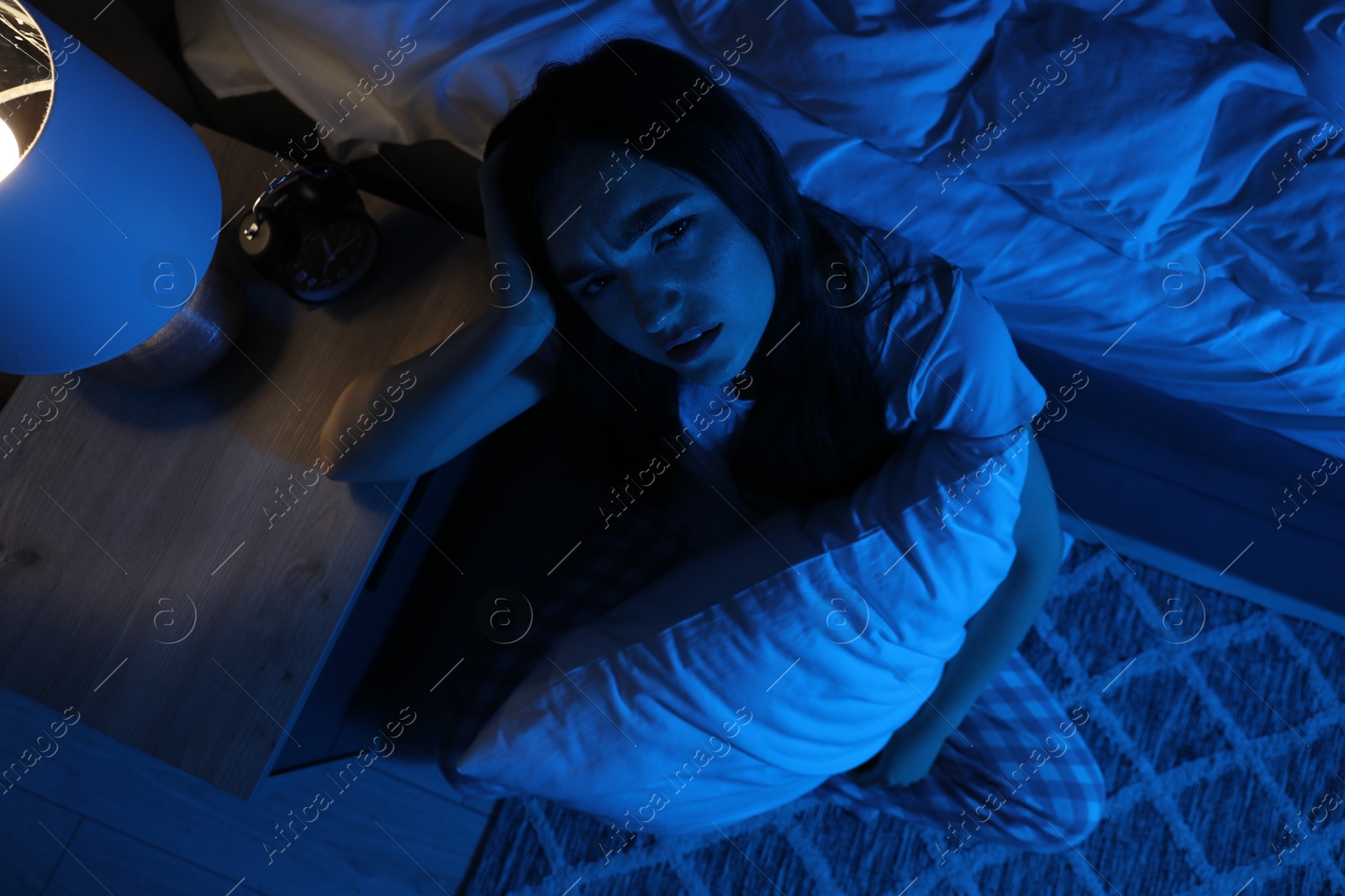 Frustrated woman with pillow suffering from insomnia on floor at home, top view Photo of Frustrated woman with pillow suffering from insomnia on floor at home, top view