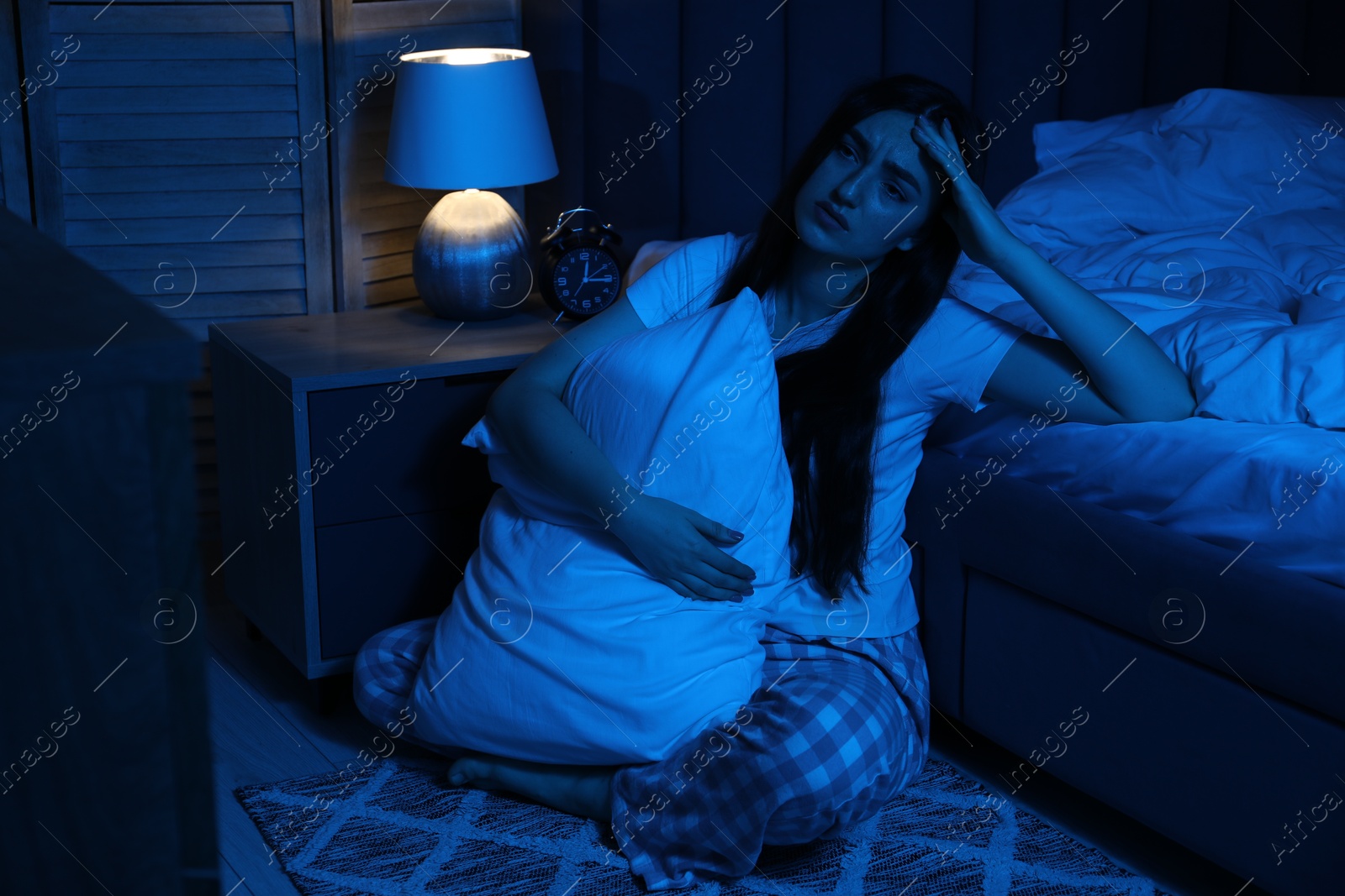 Frustrated woman with pillow suffering from insomnia on floor at home Photo of Frustrated woman with pillow suffering from insomnia on floor at home