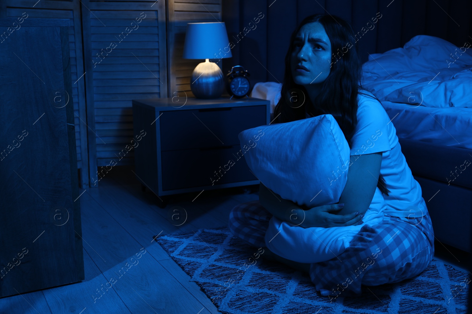 Frustrated woman with pillow suffering from insomnia on floor at home Photo of Frustrated woman with pillow suffering from insomnia on floor at home