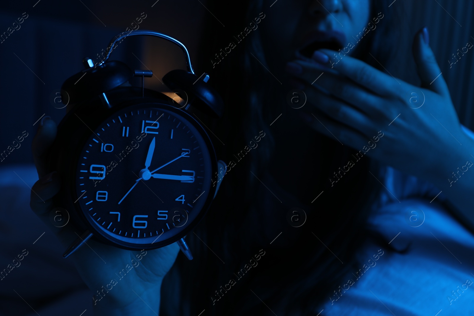 Frustrated woman with alarm clock suffering from insomnia on bed at home, closeup Photo of Frustrated woman with alarm clock suffering from insomnia on bed at home, closeup