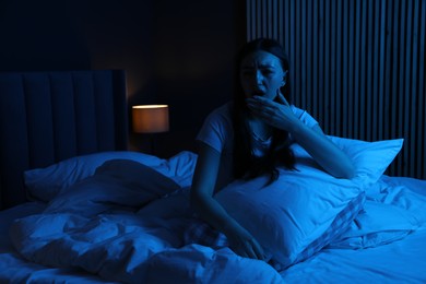 Photo of Frustrated woman with pillow suffering from insomnia on bed at home