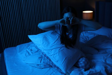 Photo of Frustrated woman with pillow suffering from insomnia on bed at home