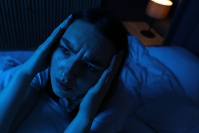 Photo of Frustrated woman with pillow suffering from insomnia on bed at home