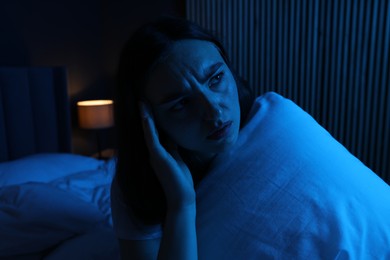 Photo of Frustrated woman with pillow suffering from insomnia on bed at home