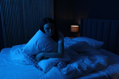 Photo of Frustrated woman with pillow suffering from insomnia on bed at home