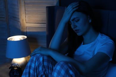 Photo of Frustrated woman suffering from insomnia on bed at home