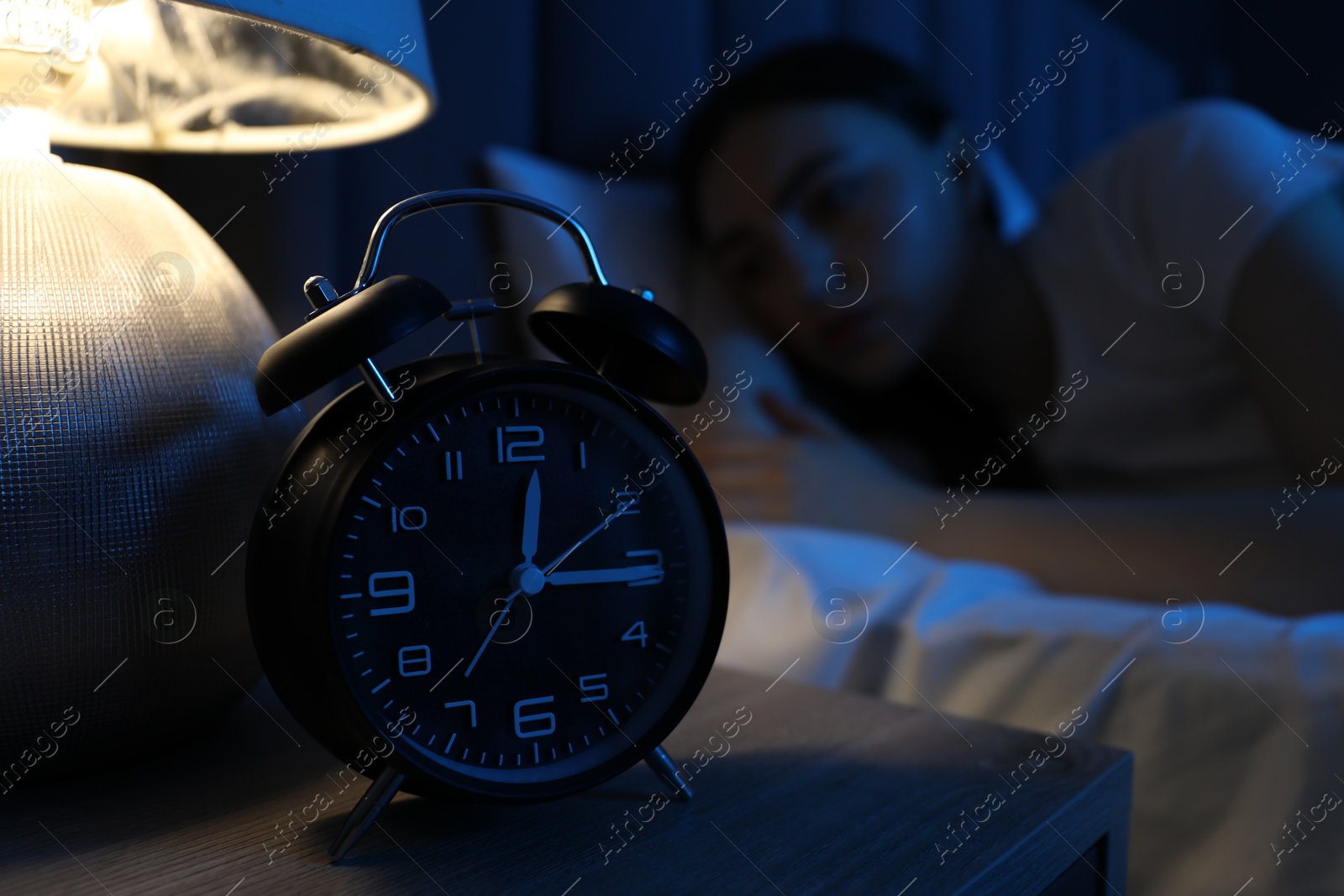 Frustrated woman suffering from insomnia in bed at home, focus on alarm clock Photo of Frustrated woman suffering from insomnia in bed at home, focus on alarm clock
